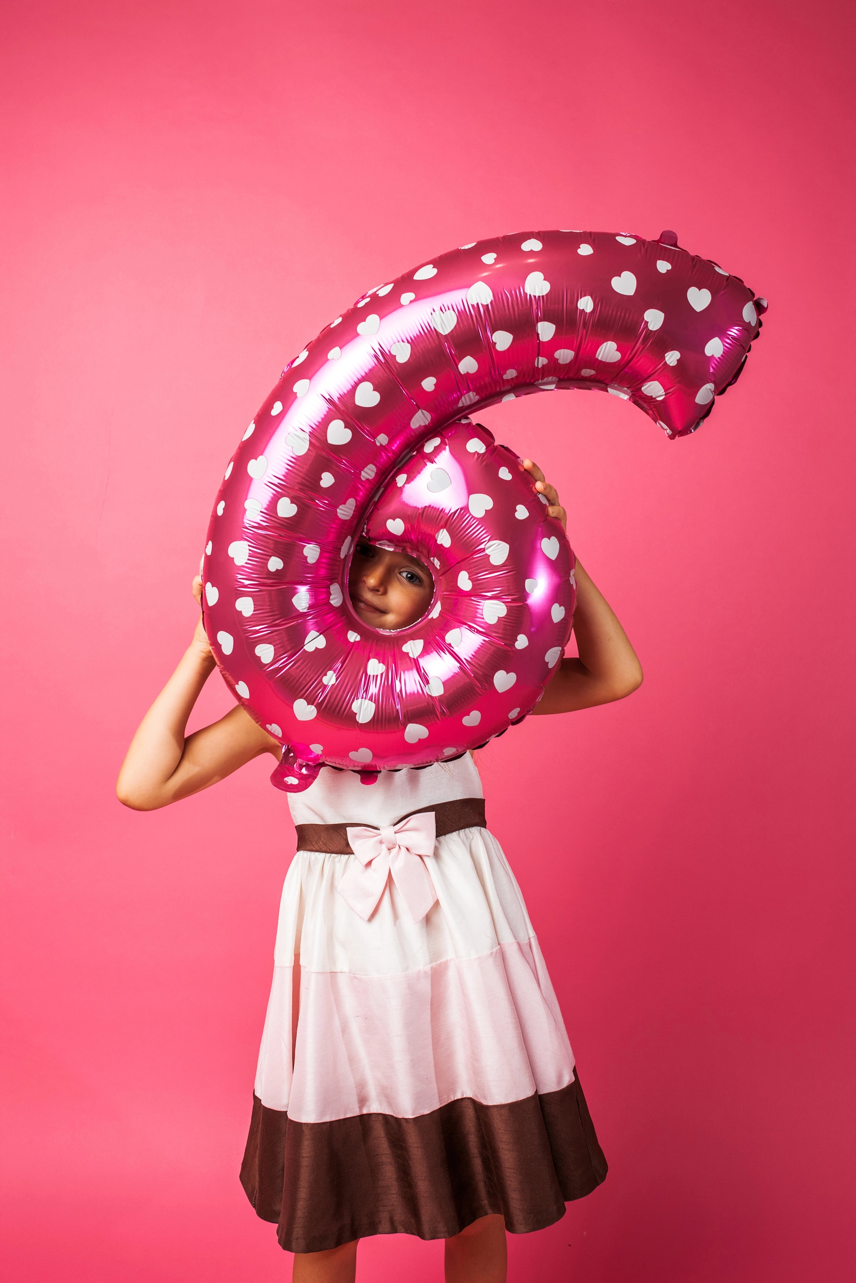 Mädchen mit rosa Luftballon in Form der Zahl 6 feiert Kindergeburtstag im Little Beauty Spa mit Beauty- und Wellness-Angeboten für Mädchen.