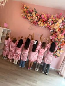 Mädchen in rosa Bademänteln vor Blumenwand im Little Beauty Spa